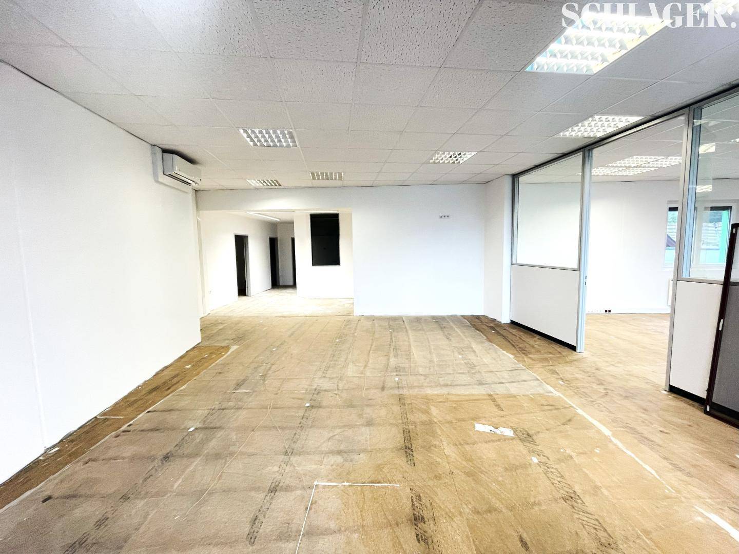 Großer, leerer Bürobereich mit Glasabtrennungen, Klimaanlage und vorbereitetem Boden.