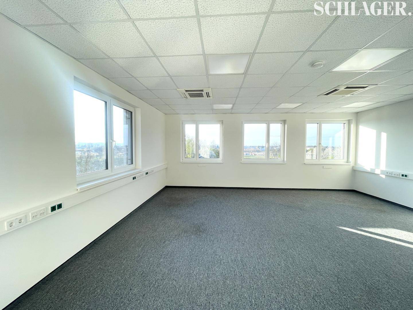 Heller Eckbüroraum mit vielen Fenstern, die eine weite Aussicht und reichlich natürliches Licht bieten.