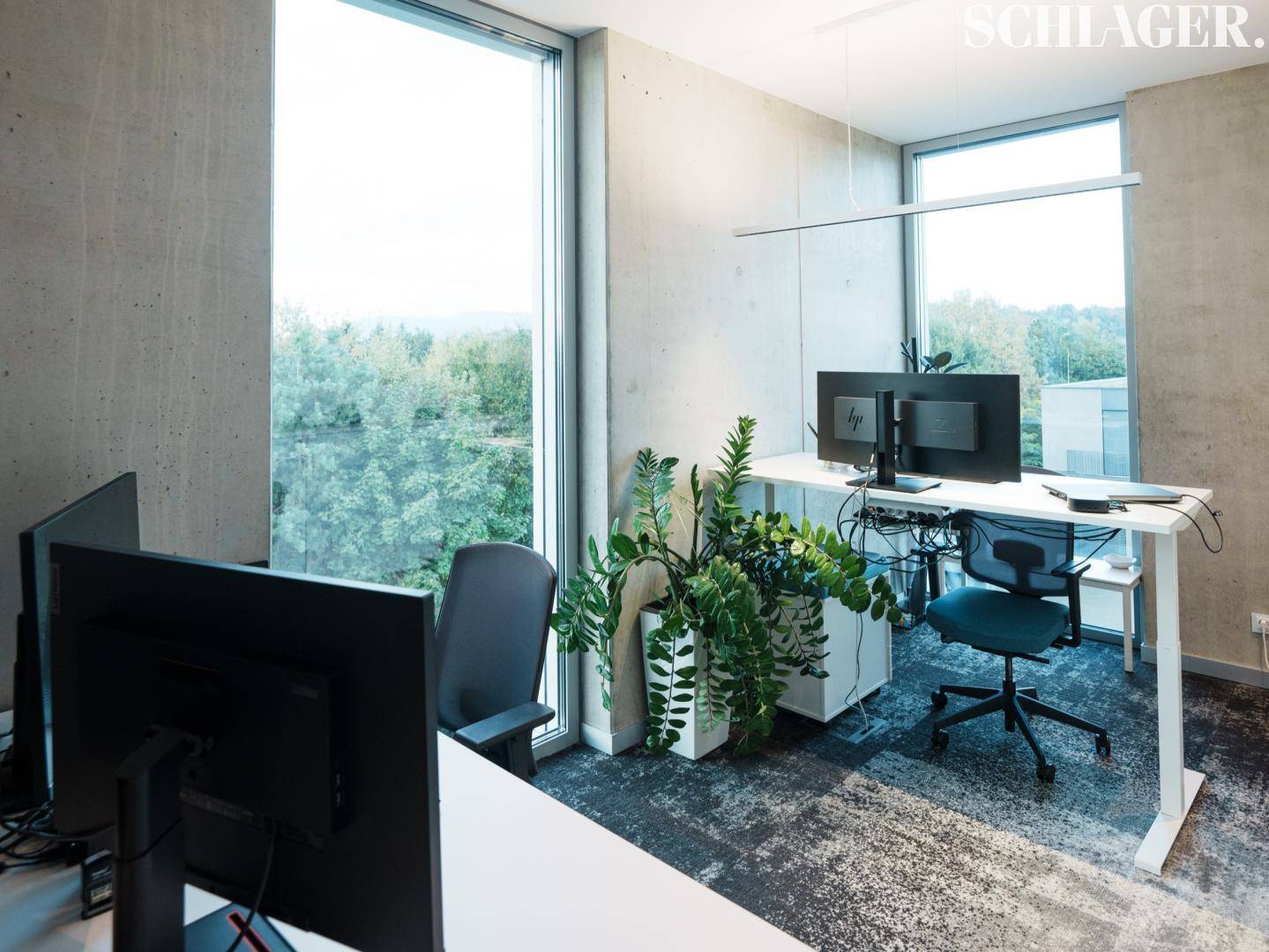 Helles Büro mit zwei Arbeitsplätzen und raumhohen Fenstern, die viel Tageslicht hereinlassen.