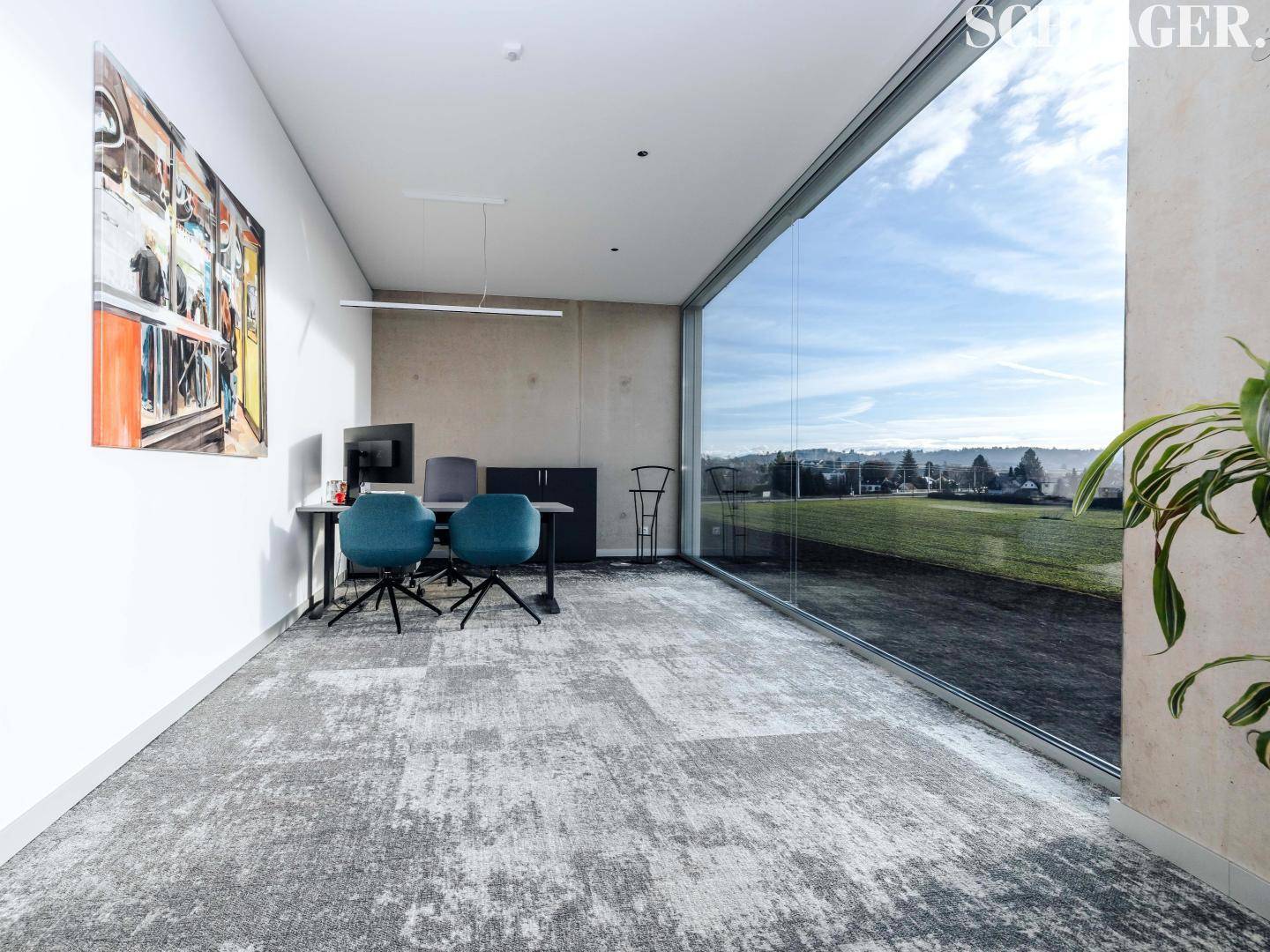 Modernes Büro mit großem Fenster, das einen weiten Blick auf die Landschaft bietet.