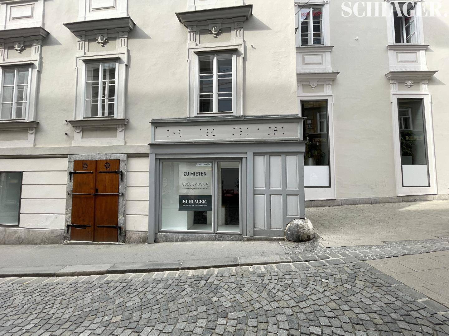 Fassade eines historischen Gebäudes mit Ladenlokal im Erdgeschoss und einem 'Zu vermieten'-Schild.