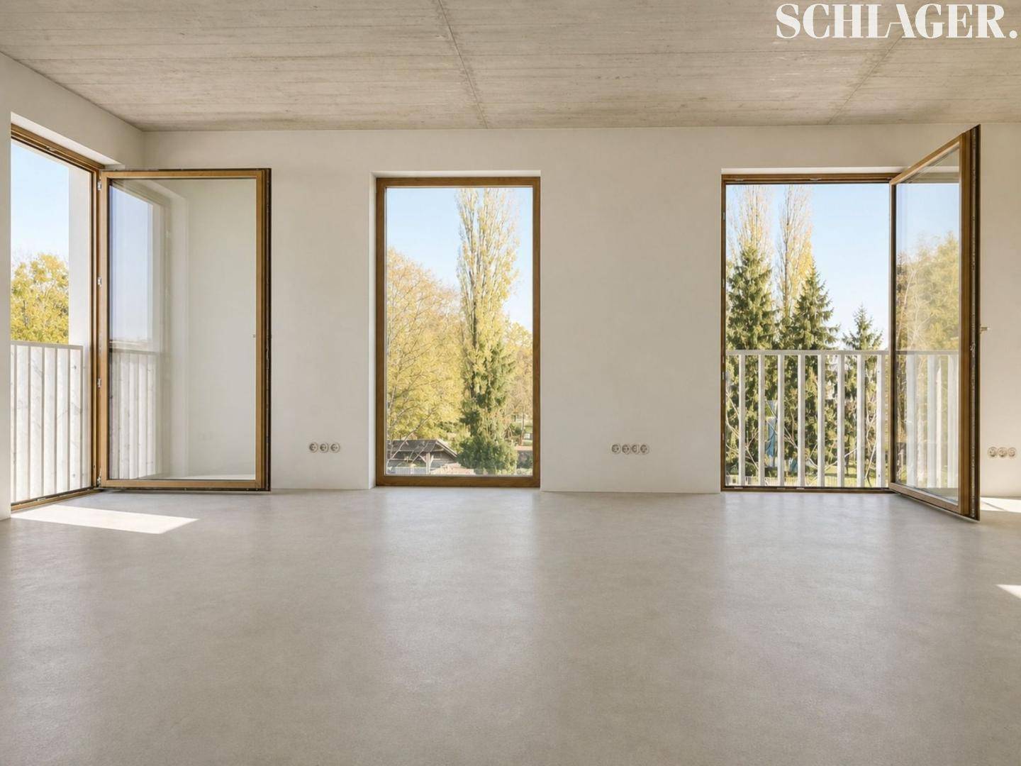 Heller Wohnbereich mit raumhohen Fenstern, die viel Tageslicht und einen Blick ins Grüne bieten.