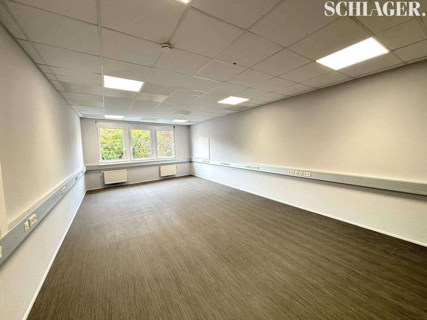 Helles Eckbüro mit mehreren Fenstern, praktischen Kabelkanälen und abgehängter Decke.