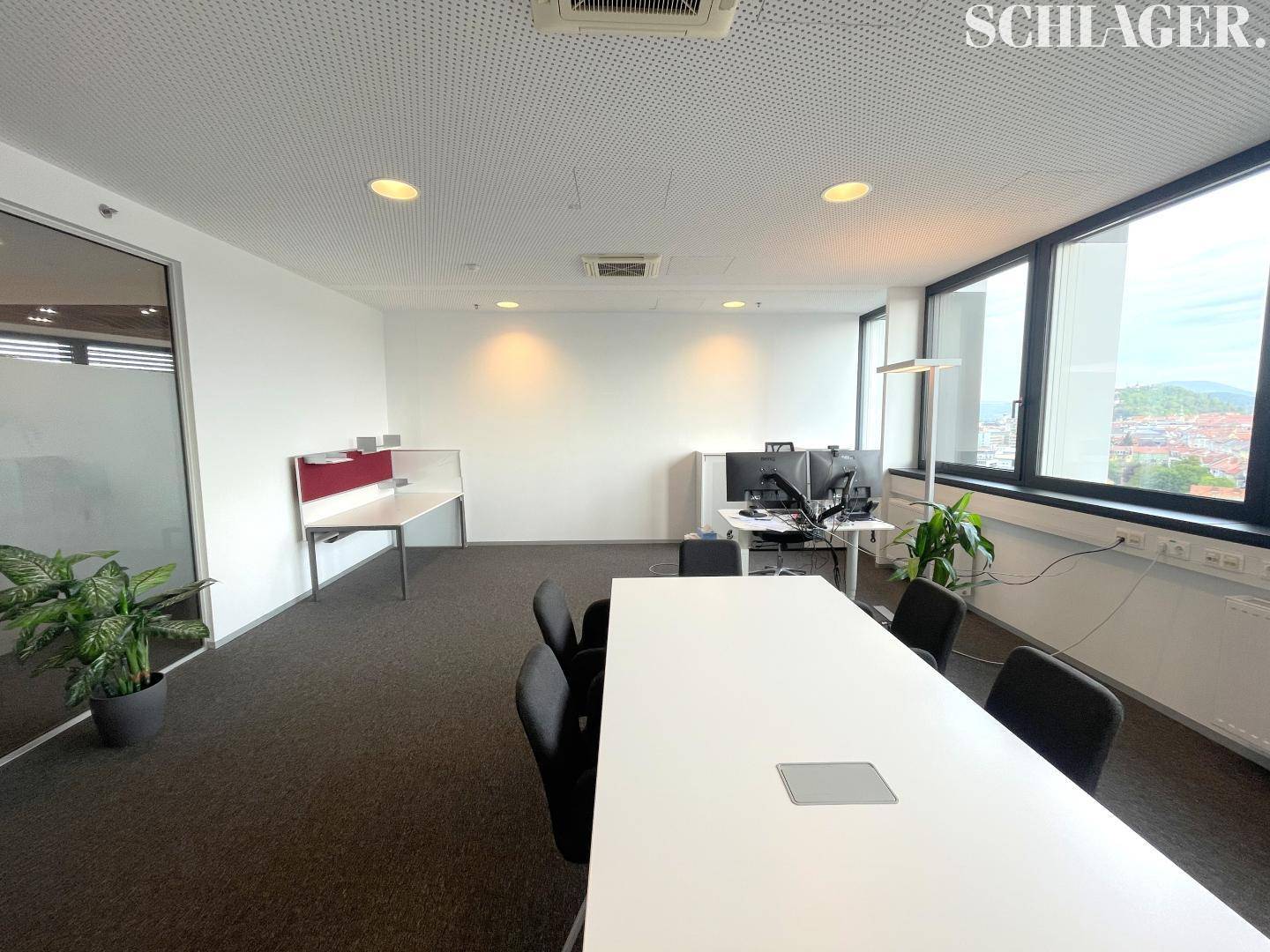 Geräumiges Büro mit großem Besprechungstisch, Arbeitsplätzen und weitem Blick über die Stadt.