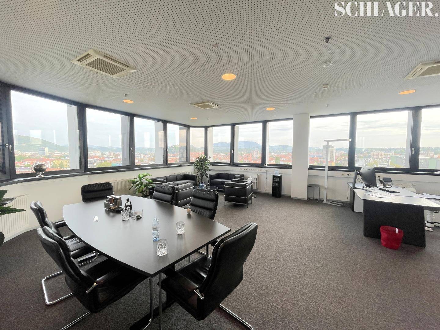 Komfortabler Bürobereich mit Ledersofas, Besprechungstisch und großen Fenstern mit Panoramablick.