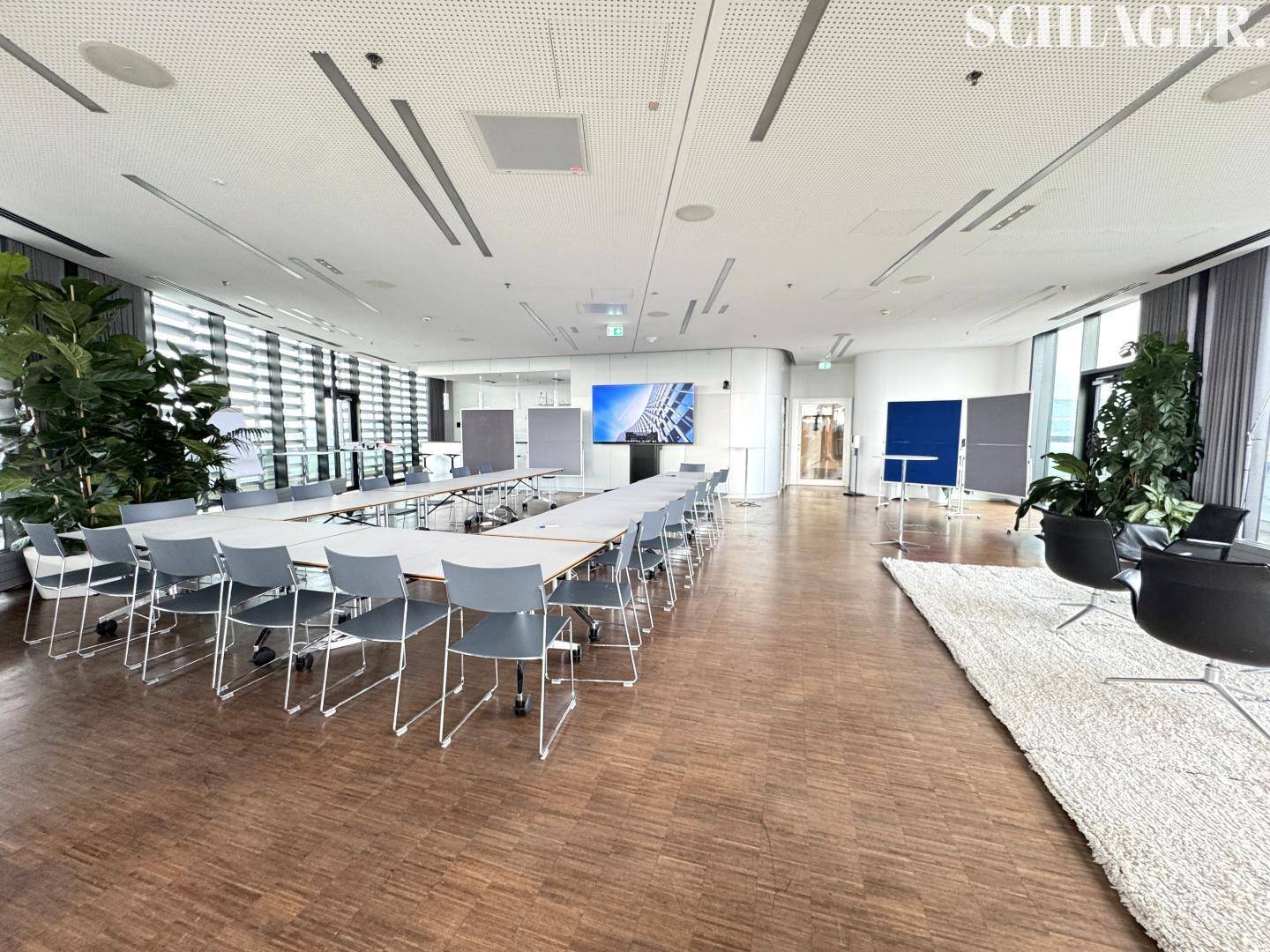 Großer Konferenzraum mit flexibler Bestuhlung, Holzboden und moderner Präsentationstechnik für Veranstaltungen.