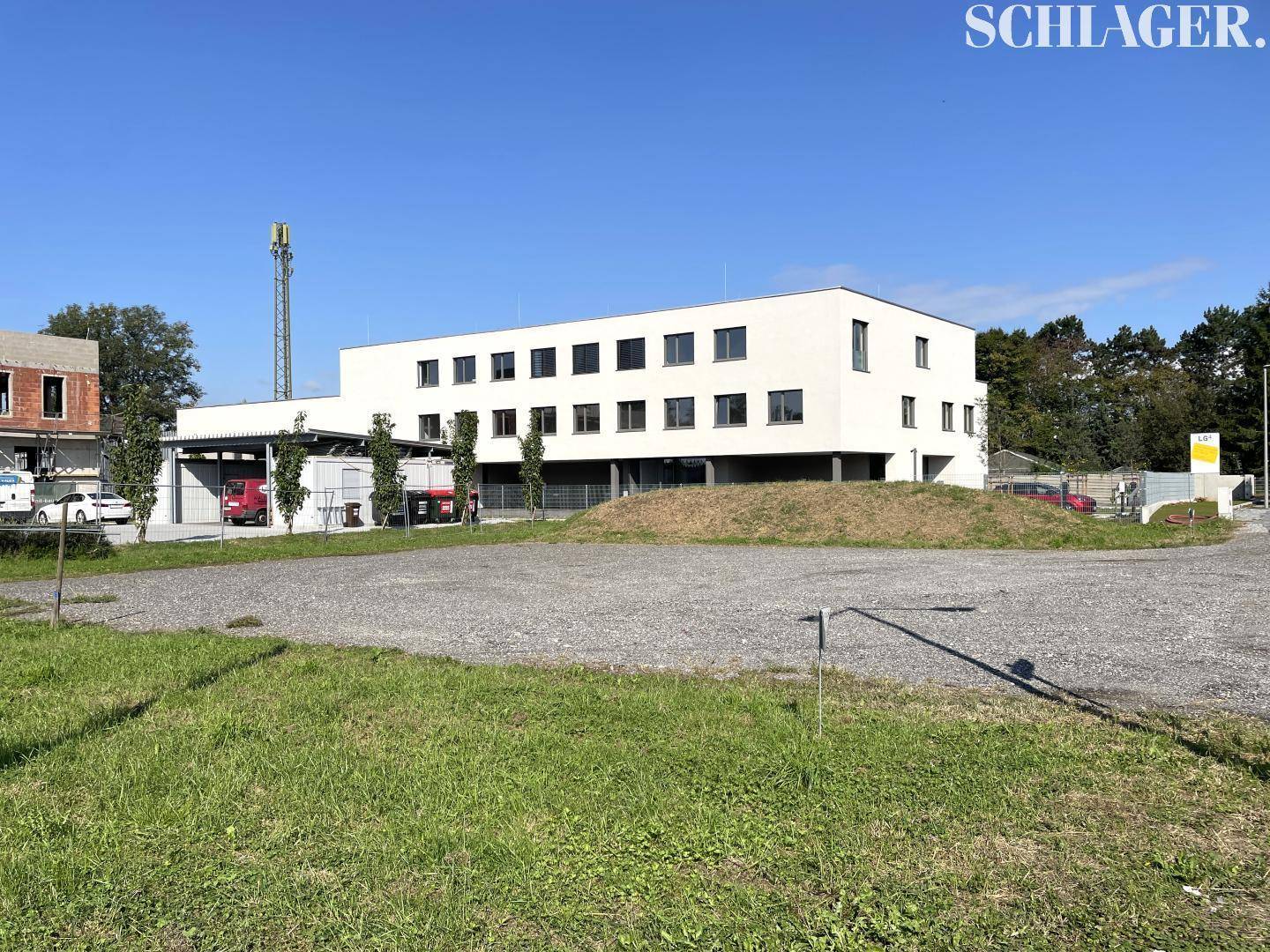 Weitläufiges Grundstück mit Schotter- und Grasflächen vor einem modernen Neubau mit Carport.