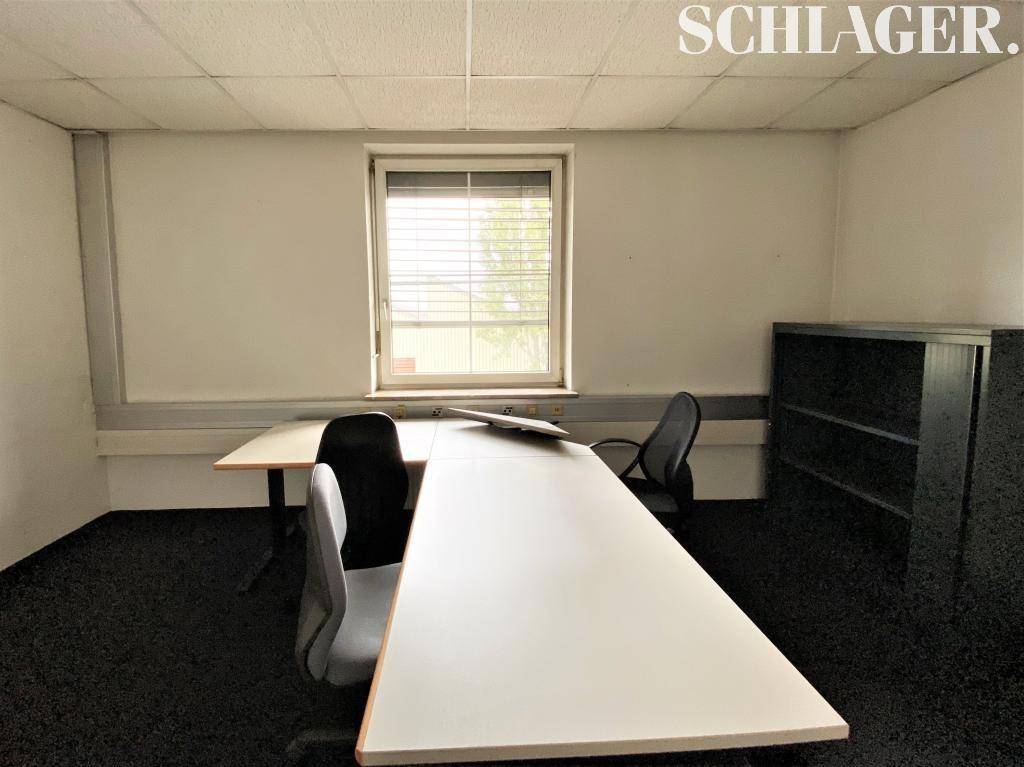 Büro mit zwei Arbeitsplätzen, einem Fenster und einem dunklen Regal, ideal für Teamarbeit.