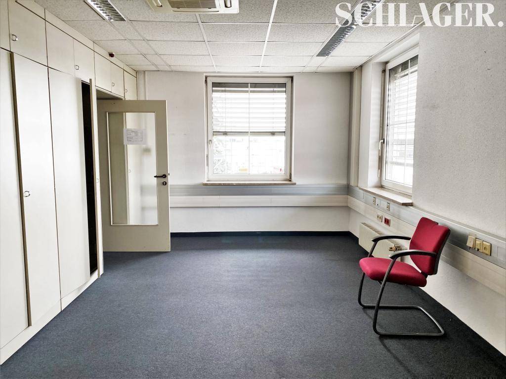 Leeres Büro mit Einbauschränken, Teppichboden und Fenstern, bereit zur individuellen Gestaltung.