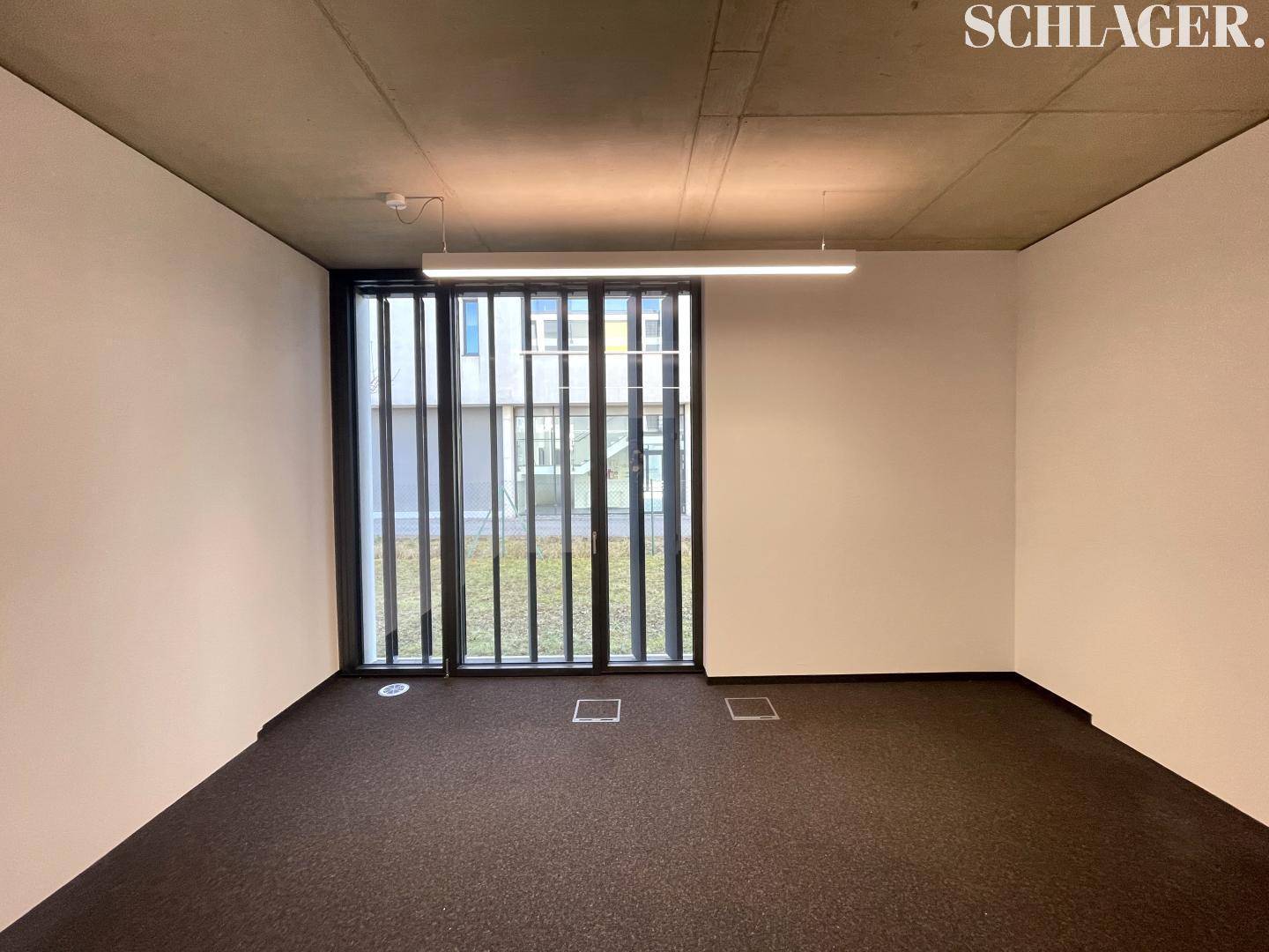 Modernes Büro mit großen Fenstern, die viel Licht spenden, und schlichtem Design.