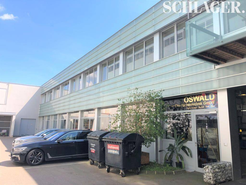 Gewerbegebäude mit moderner Fassade, Eingangsbereich und Parkmöglichkeiten für Fahrzeuge.