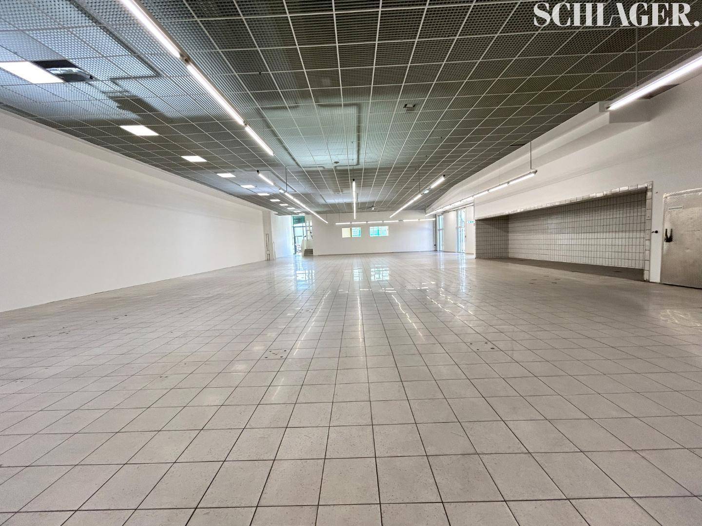 Großer, leerer Gewerberaum mit hellen Fliesenböden und Rasterdecke, bereit für neue Nutzung.