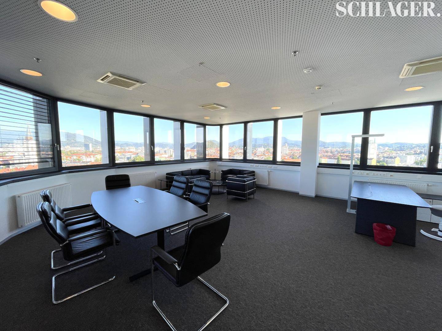 Konferenzraum mit großem Tisch, Ledersesseln und weitem Stadtblick durch Panoramafenster.
