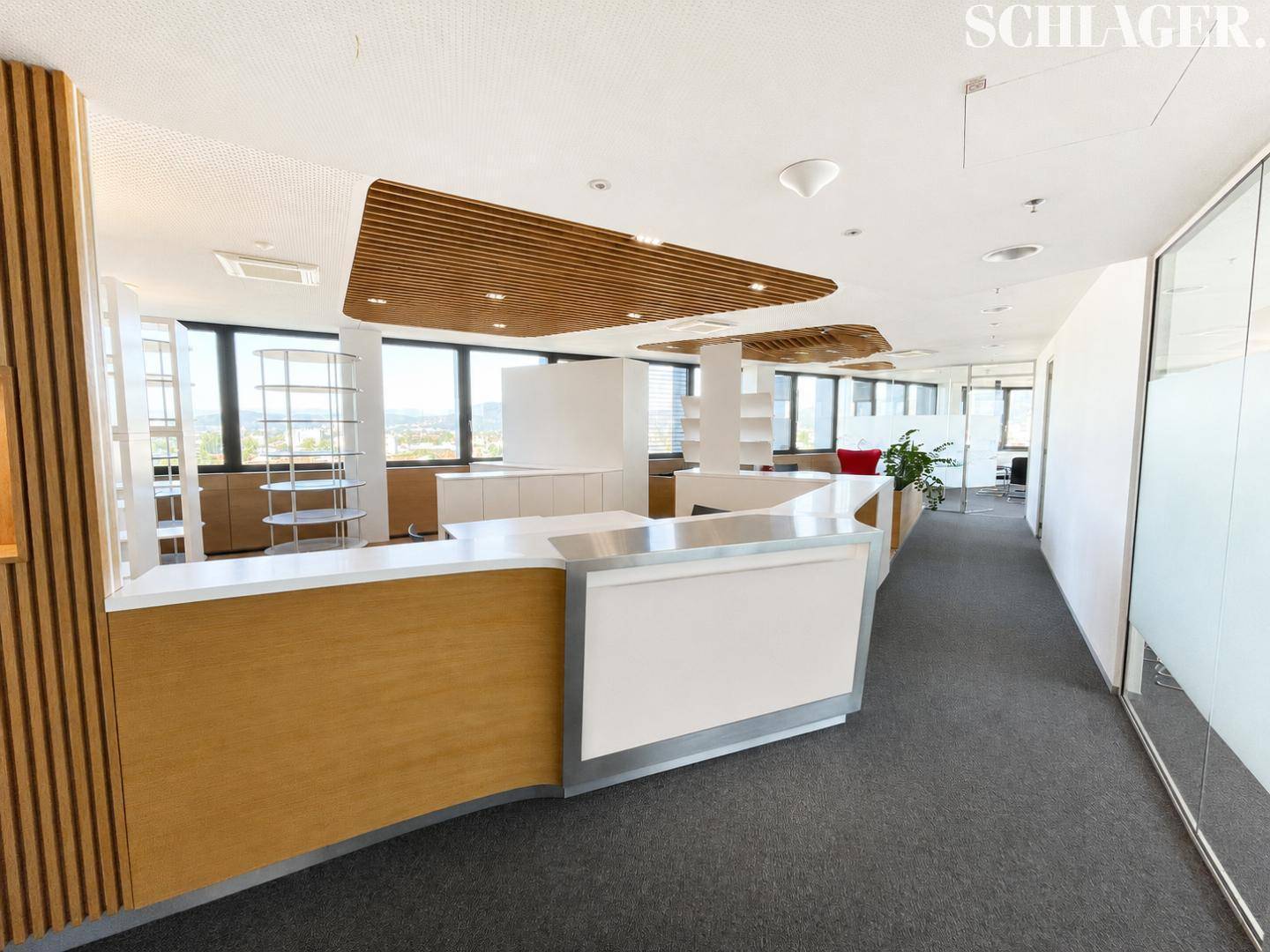 Heller Empfangsbereich in einem modernen Büro mit Teppichboden und großen Fenstern.