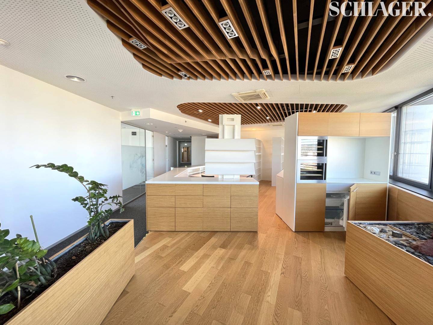 Moderne Büroküche mit Holzboden, integrierten Geräten und dekorativer Holzdeckenverkleidung.