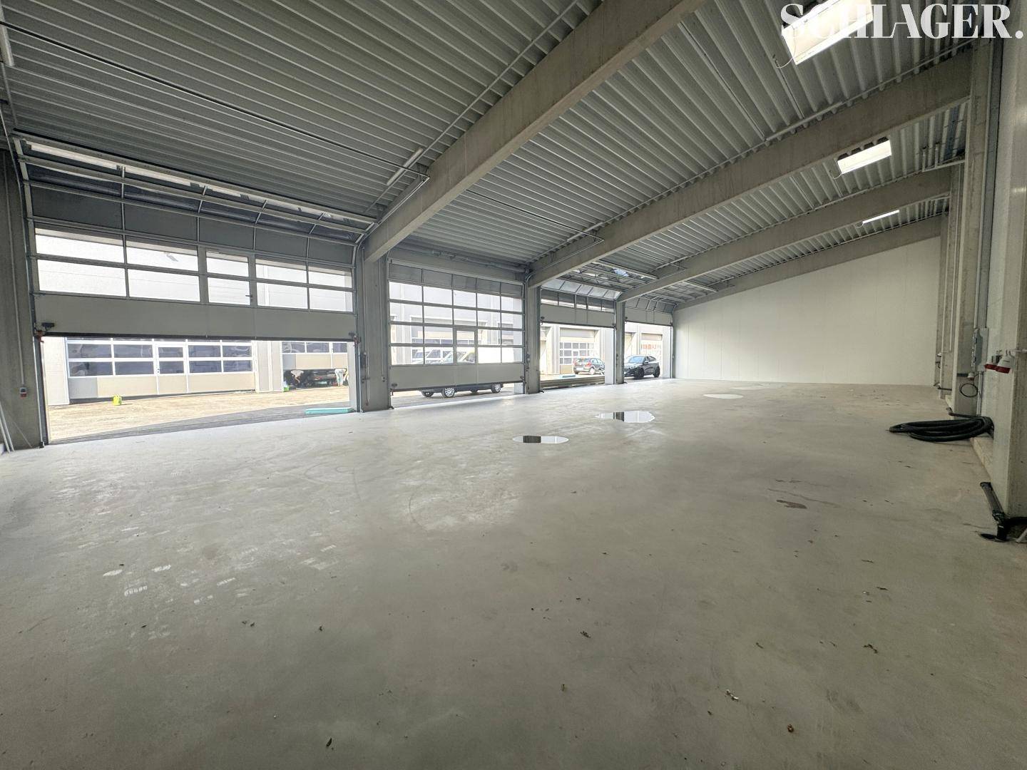 Heller und offener Innenraum einer Lagerhalle mit hohen Decken und mehreren Rolltoren für flexible Nutzung.