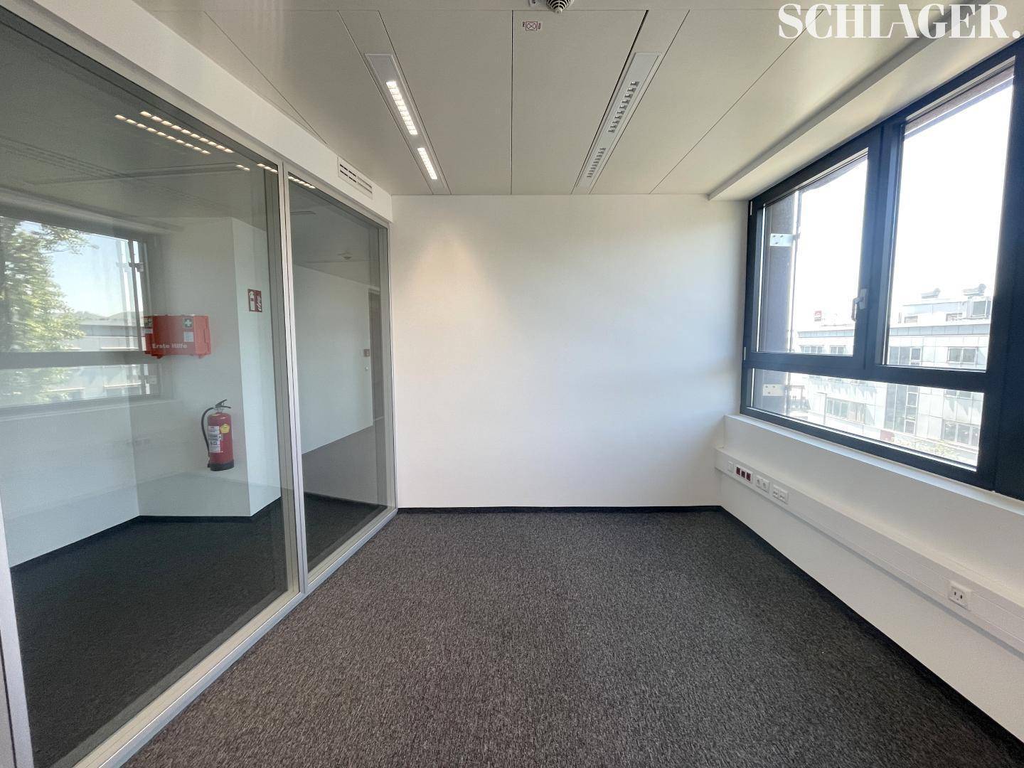 Büro mit Glaswand, Teppichboden und Feuerlöscher in der Ecke, bietet eine moderne und sichere Umgebung.