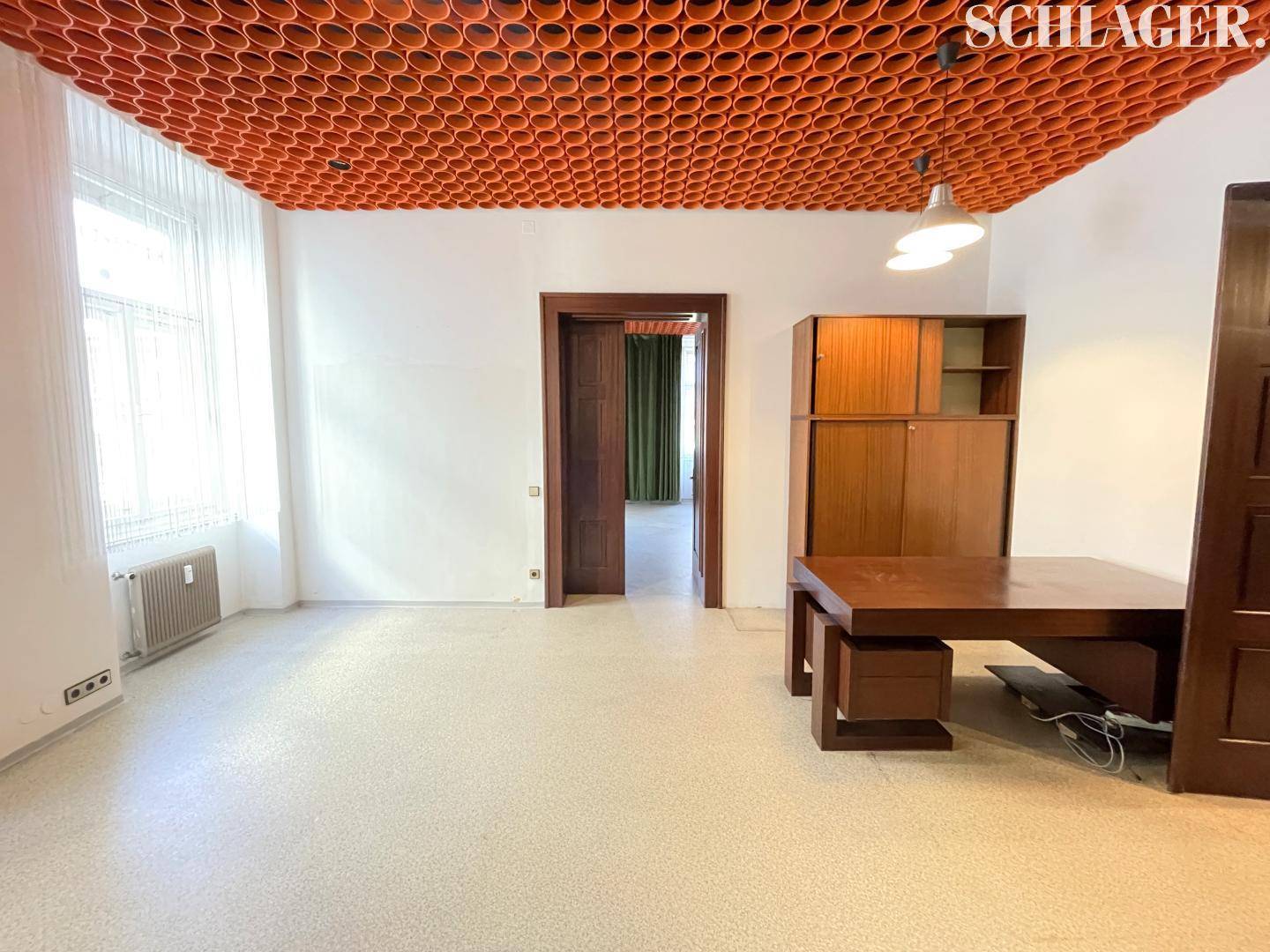 Büroraum mit einzigartiger orangefarbener Decke, Vintage-Holzmöbeln und Zugang zu einem weiteren Zimmer.