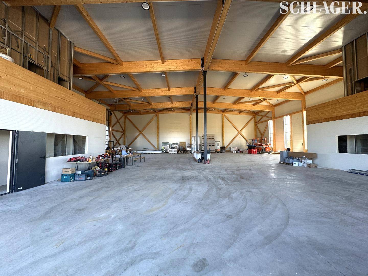 Geräumige Lagerhalle mit hohen Decken, sichtbaren Holzträgern und einem Betonboden.