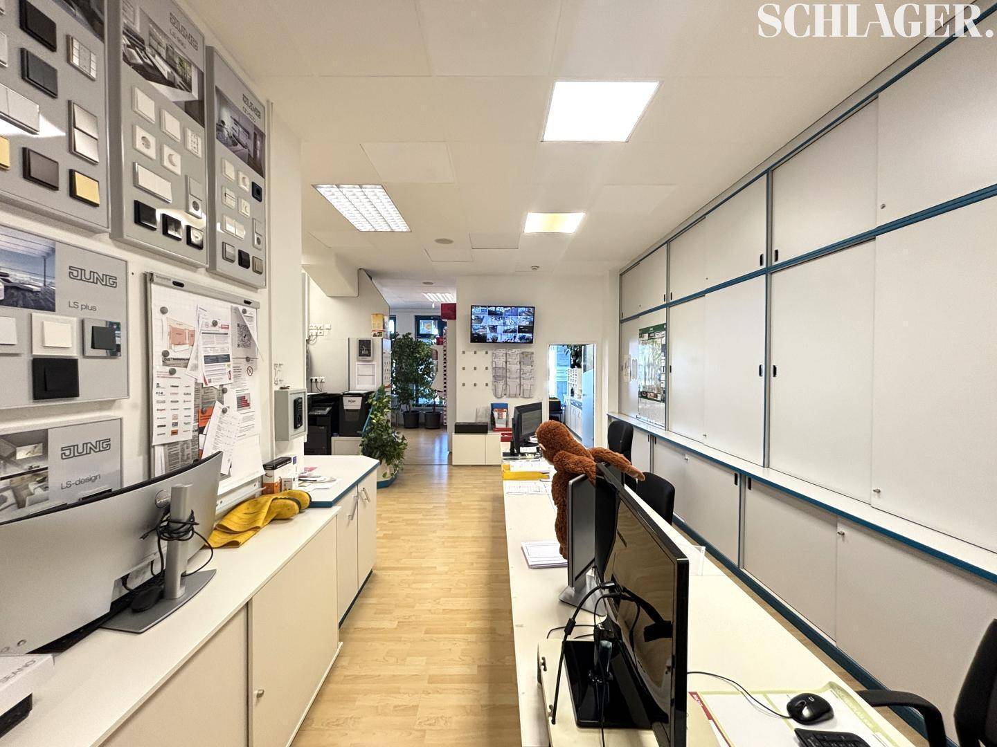 Ein langer Verkaufsraum oder Showroom mit Ausstellungsflächen, Theken und integrierten Schränken.