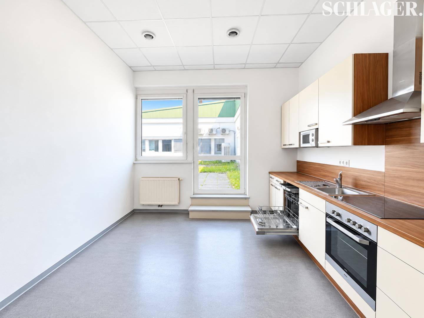 Funktionale Einbauküche mit Holztheke, integrierten Geräten und Zugang zu einem Außenbereich durch eine Tür.