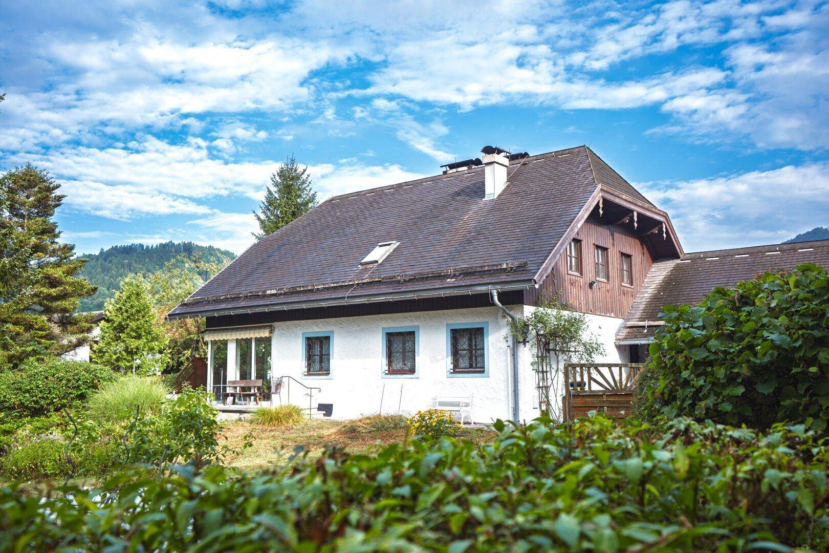 Seitenansicht des Hauses mit Terrasse, Garten und Blick auf die umliegende Natur.