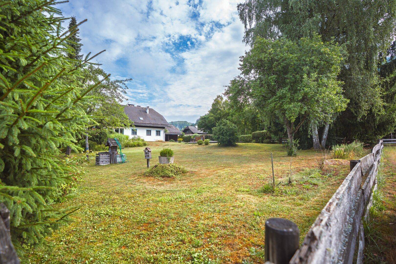 Großer Garten mit Rasenfläche, altem Baumbestand und Blick auf das charmante Wohnhaus im Grünen.