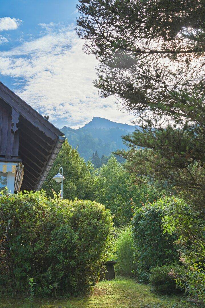 Idyllischer Gartenweg mit üppigem Grün und einem malerischen Blick auf die umliegenden Berge.