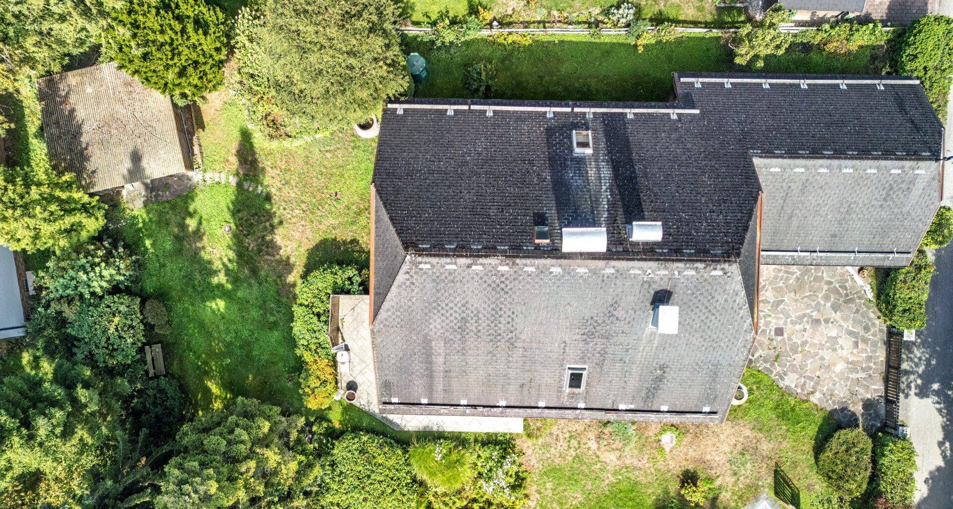 Luftaufnahme des Hauses mit Satteldach, umgeben von einem großen grünen Grundstück.