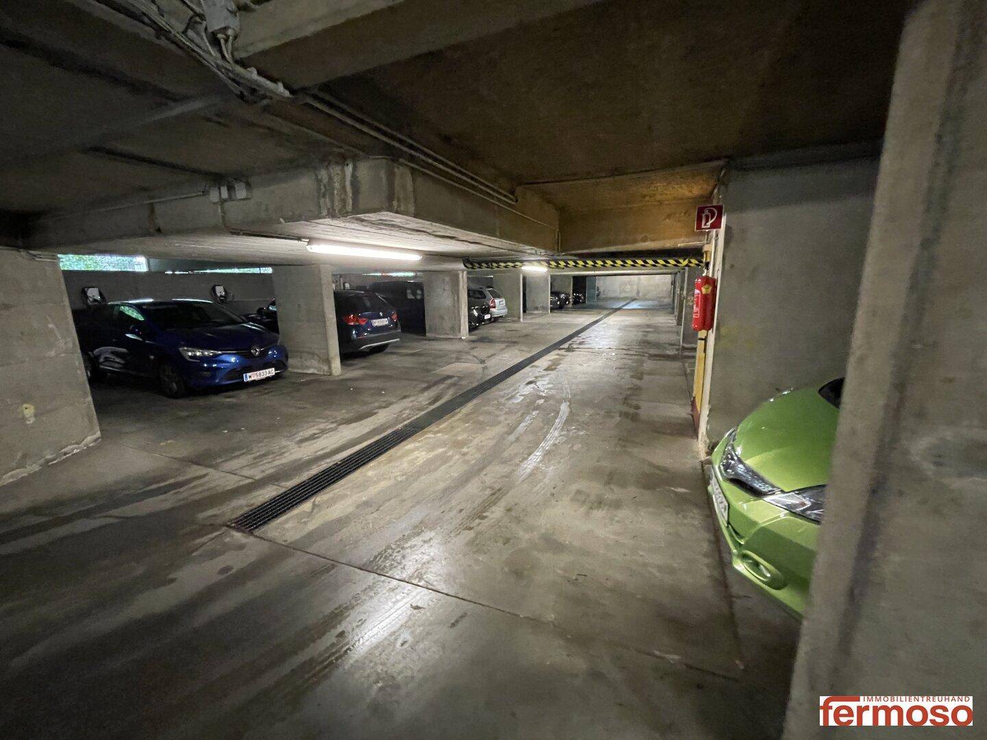 Geräumige Tiefgarage mit mehreren Stellplätzen, Betonwänden und Deckenbeleuchtung.