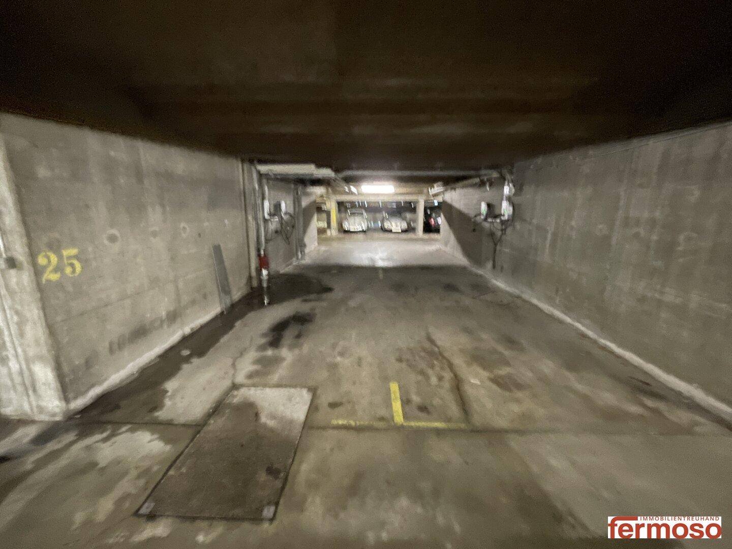 Weitläufiger Bereich in der Tiefgarage mit Betonboden und sichtbaren Markierungen.