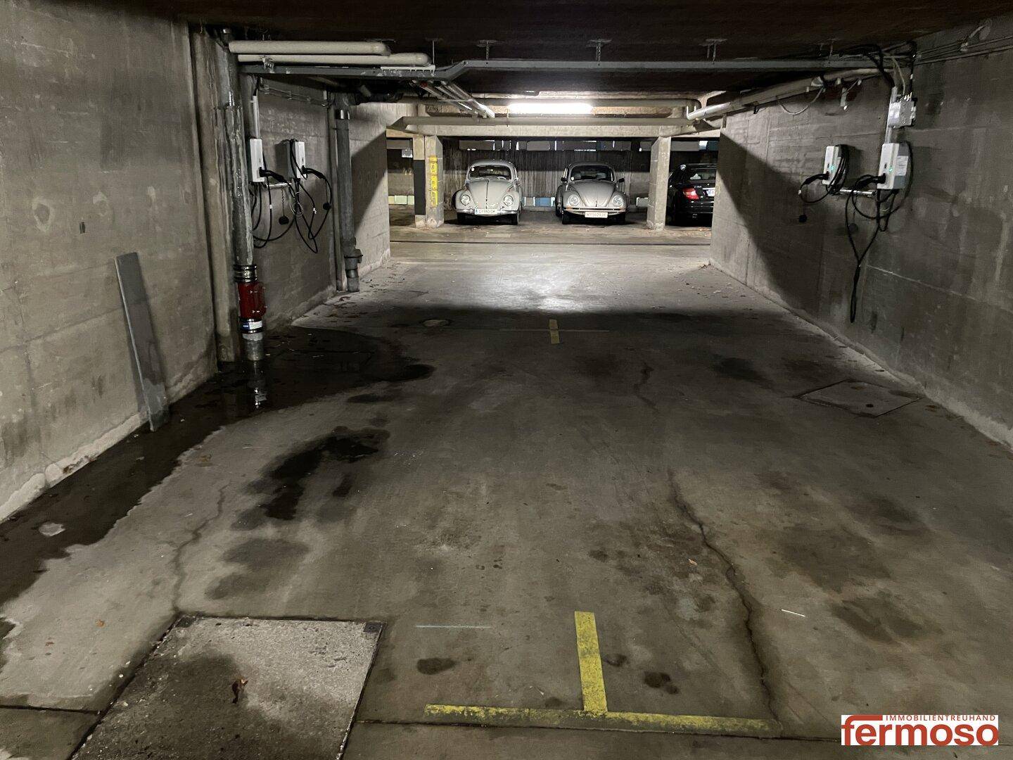 Tiefgarage mit geparkten Oldtimern und Betonwänden, gut beleuchtet.