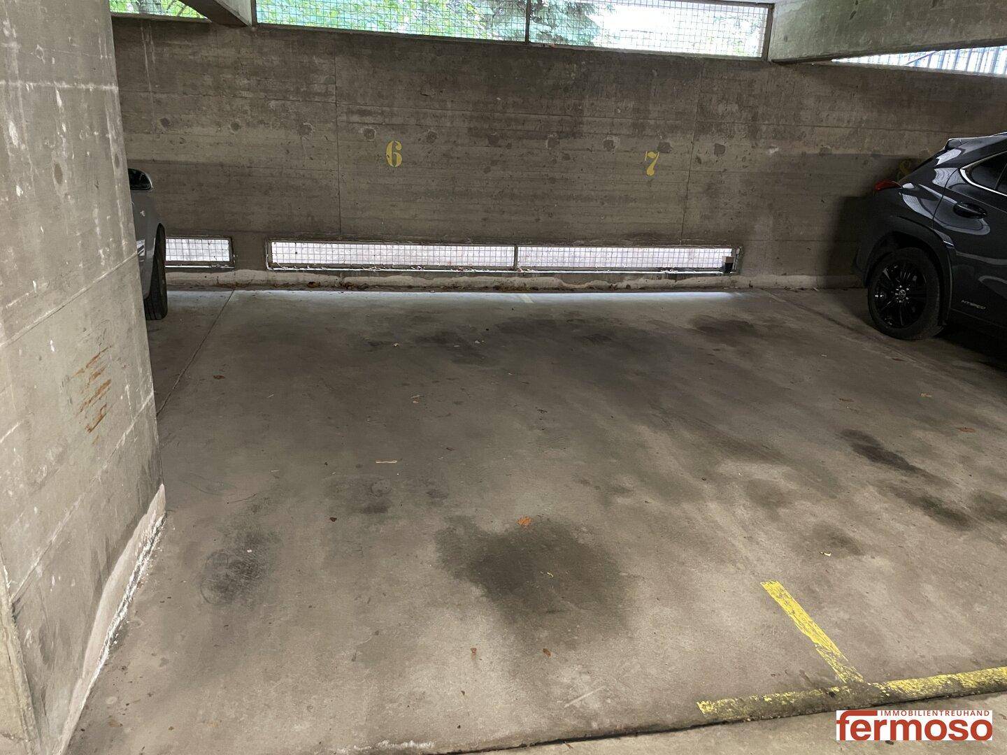 Leerer Stellplatz in der Tiefgarage mit Betonwänden und Markierungen am Boden.