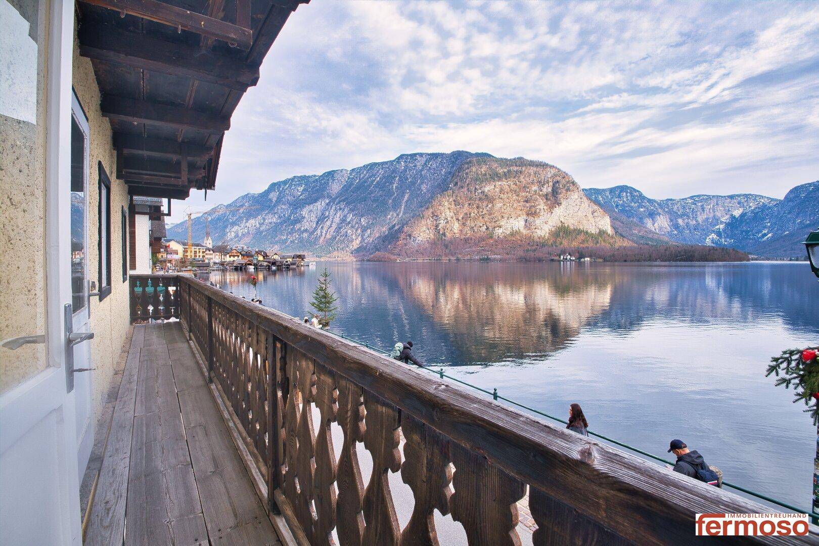 Langer Holzbalkon mit Seeblick und majestätischer Bergkulisse im Hintergrund, ideal zum Entspannen.
