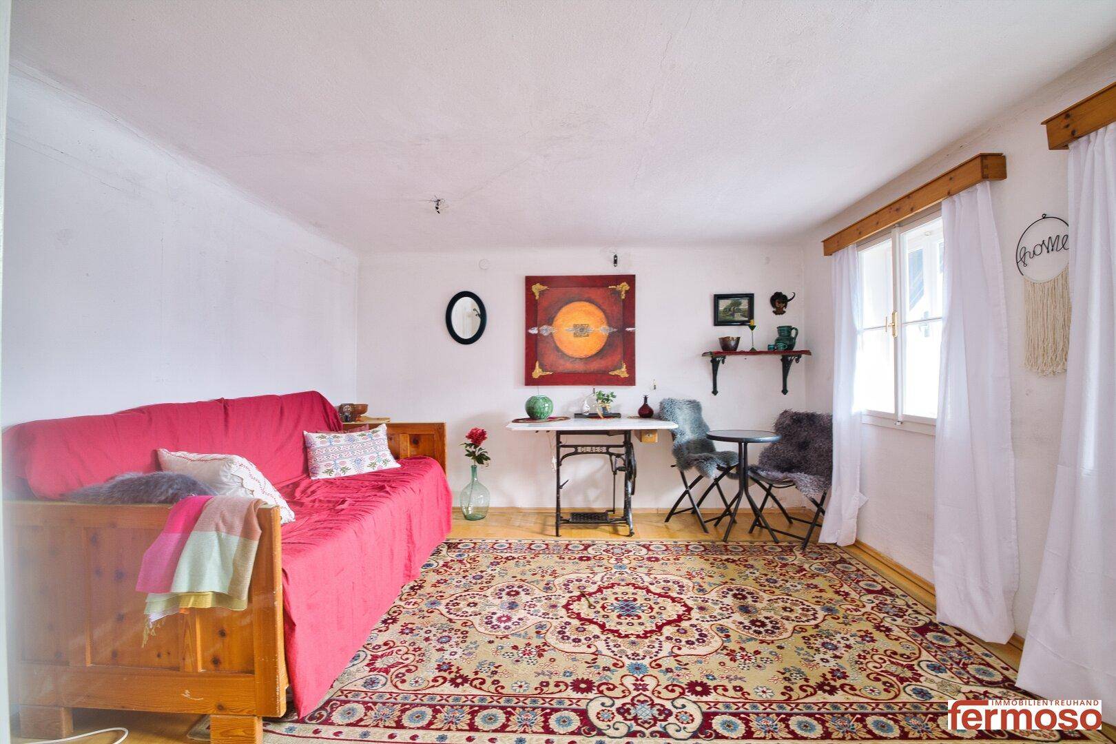 Wohnzimmer mit rotem Sofa, gemustertem Teppich und traditioneller Einrichtung, hell und einladend.