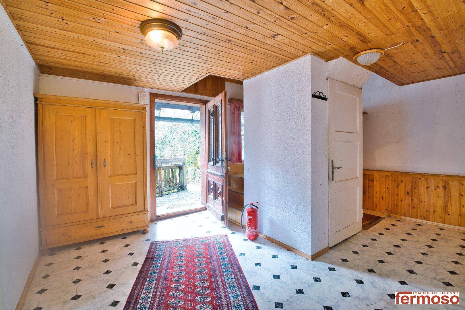 Geräumiger Eingangsbereich mit Holzdecke, Einbauschrank und Zugang zum Außenbereich.