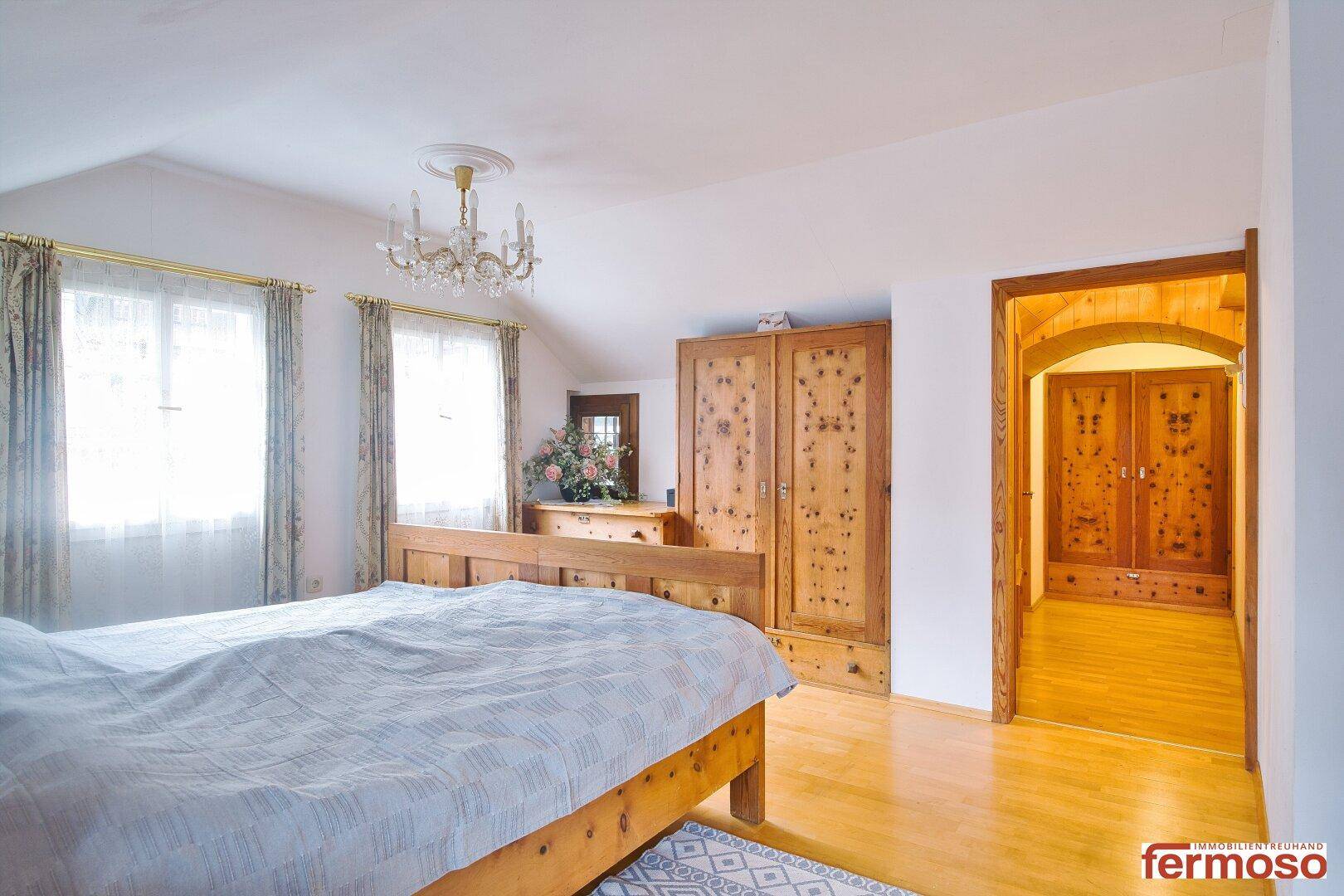 Gemütliches Schlafzimmer mit traditionellem Holzbett und passendem Kleiderschrank, mit Zugang zu einem weiteren Raum.