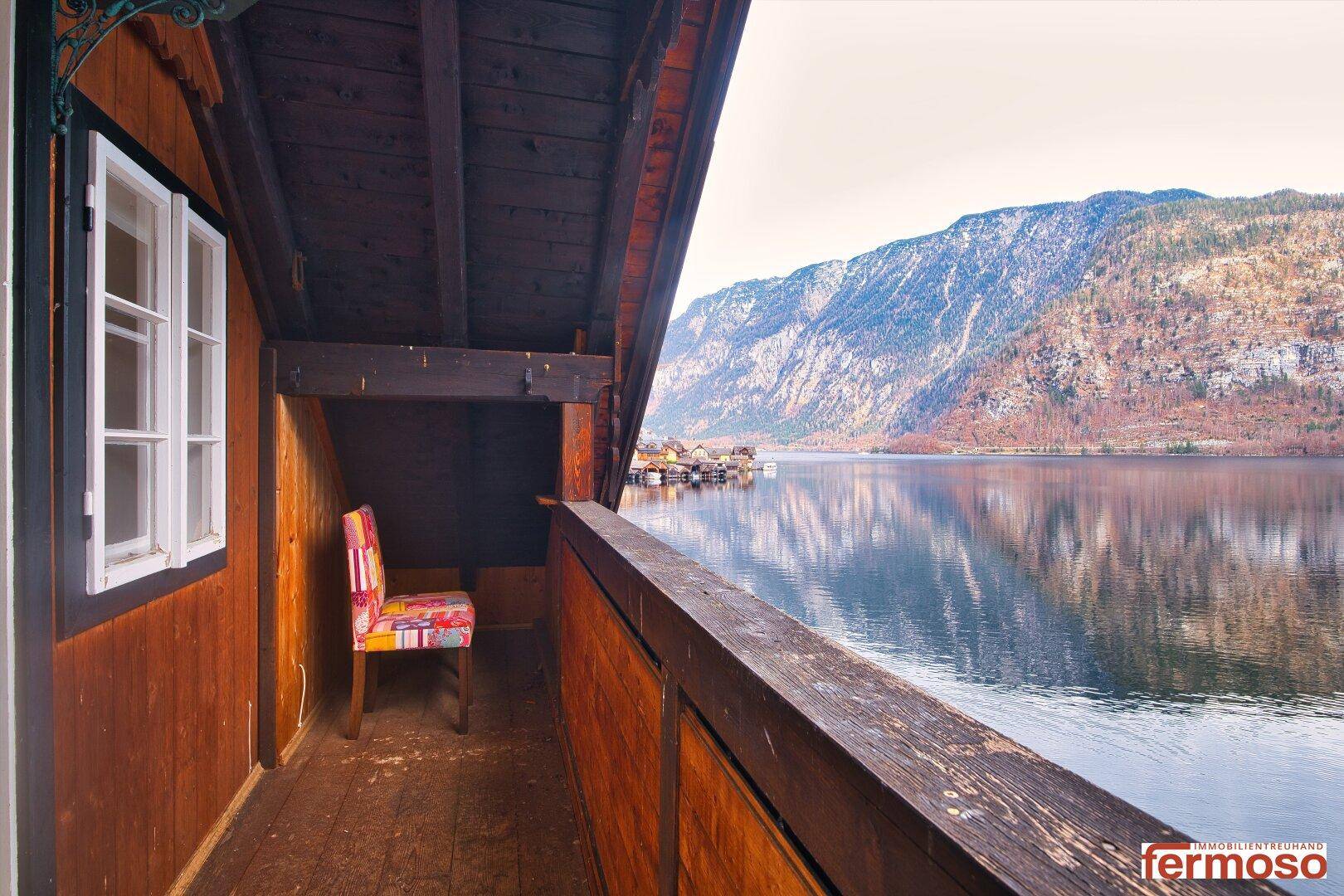 Überdachter Holzbalkon mit atemberaubendem Blick auf den See und die umliegenden Berge.