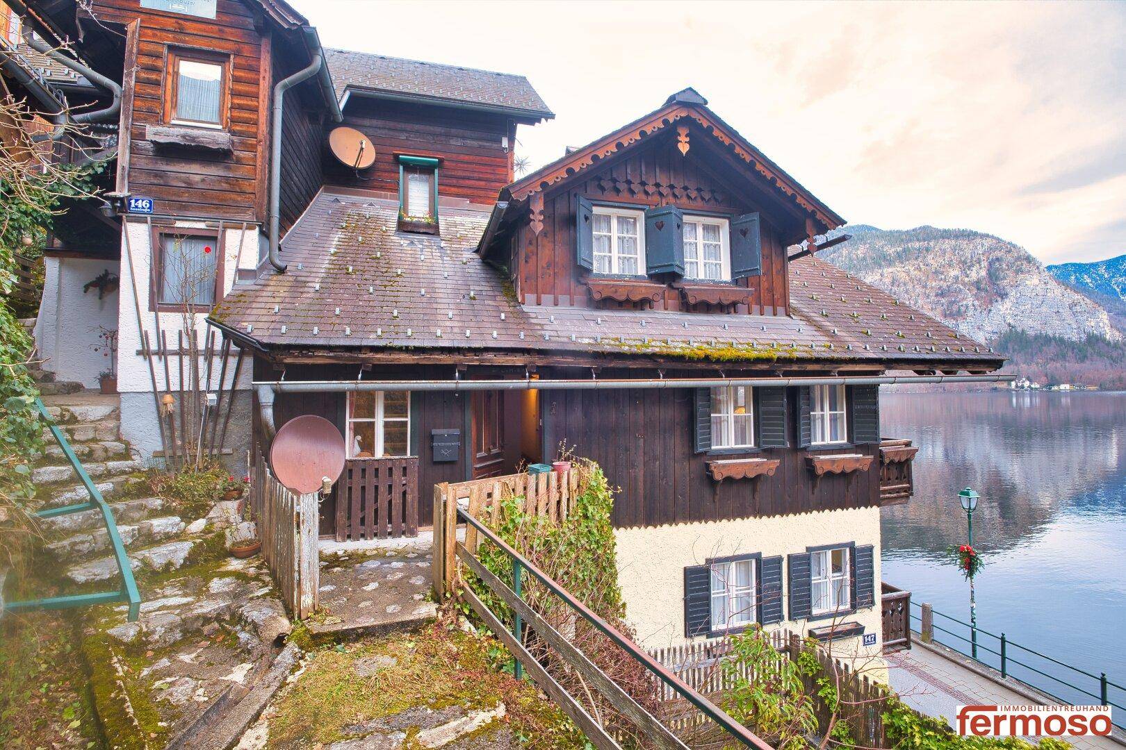 Charmantes Holzhaus am Seeufer mit traditioneller Architektur und Blick auf die Berge.