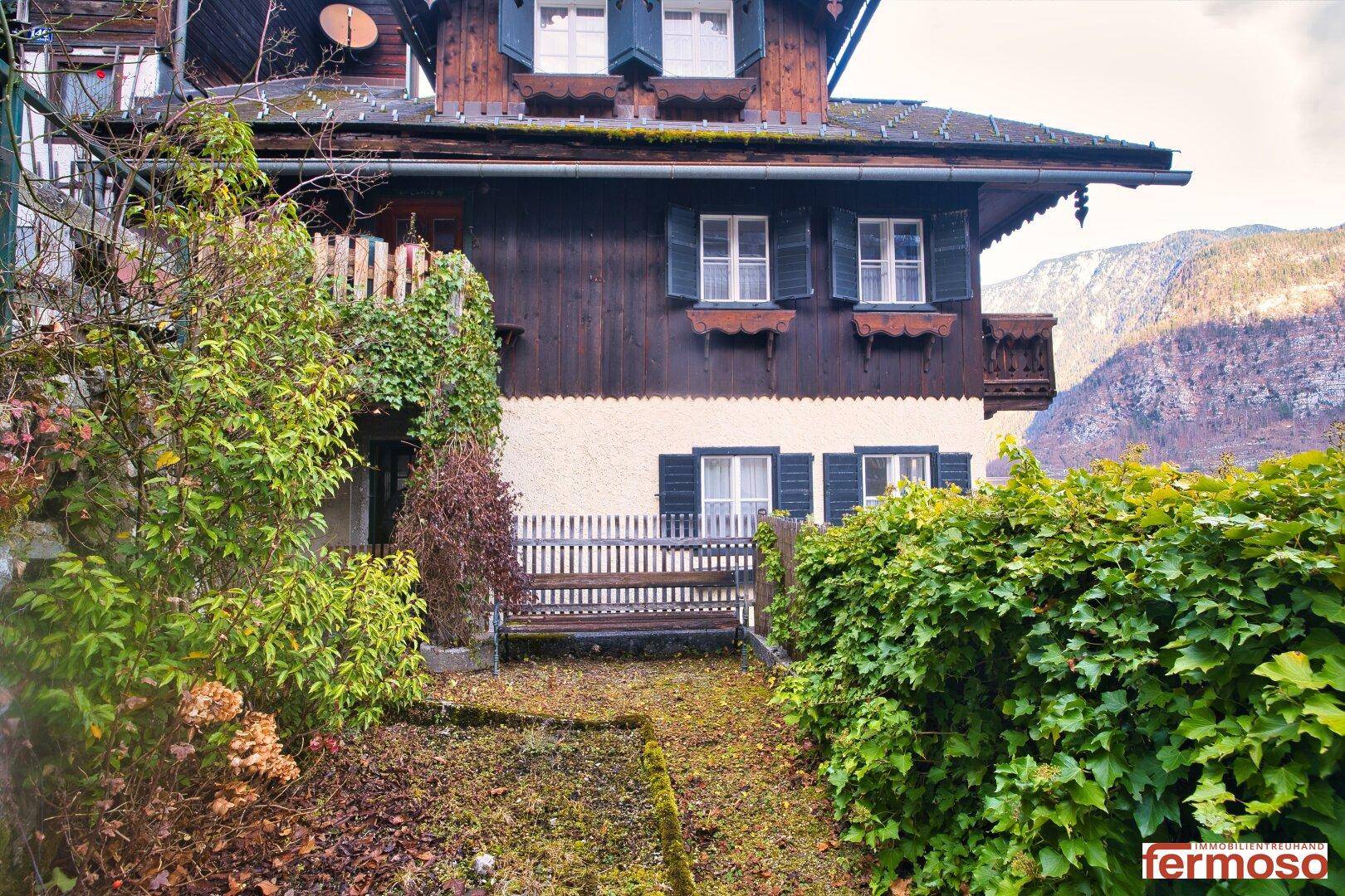 Traditionelles Haus mit kleinem Vorgarten und Blick auf die umliegenden Berge.
