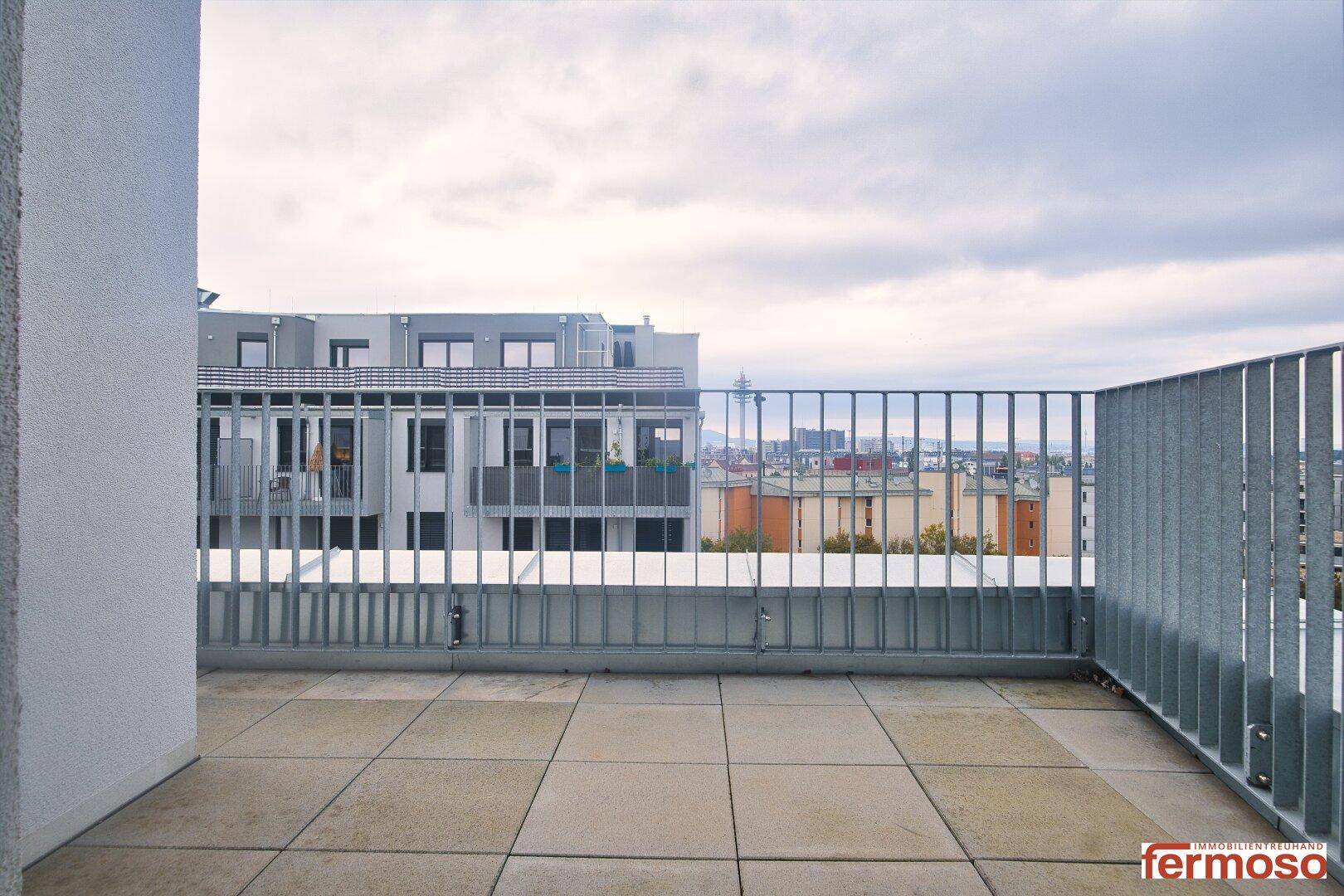 Geräumige Terrasse mit Fliesenboden und Blick auf die umliegende Stadtbebauung.