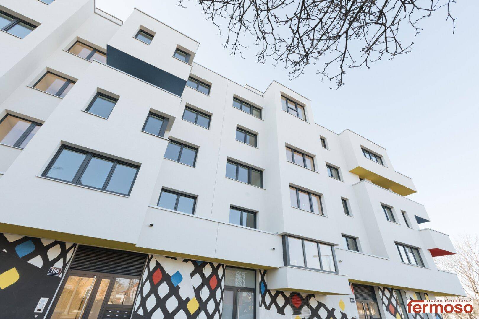 Ansicht eines modernen Wohngebäudes mit weißer Fassade und vielen Fenstern.