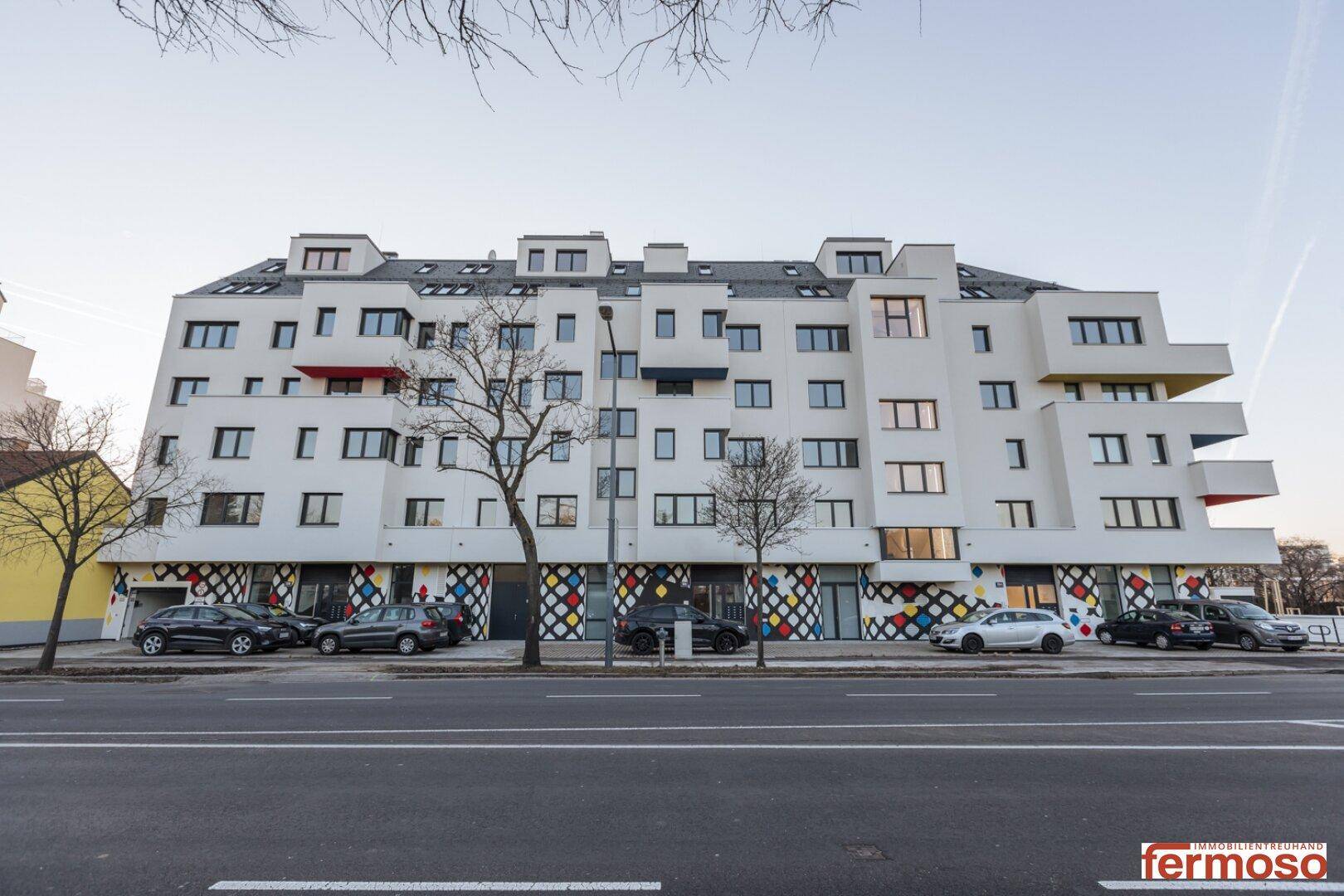 Gesamtansicht der modernen Wohnanlage von der Straße aus, mit farbigen Akzenten.