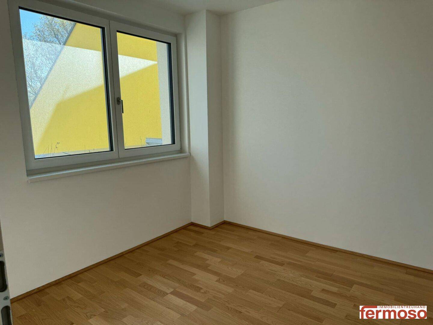 Kleineres Zimmer mit Parkettboden und Fenster, das viel Tageslicht bietet.