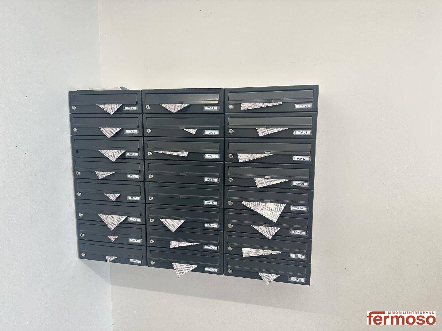 Reihe von schwarzen Briefkästen im Eingangsbereich des Wohngebäudes.