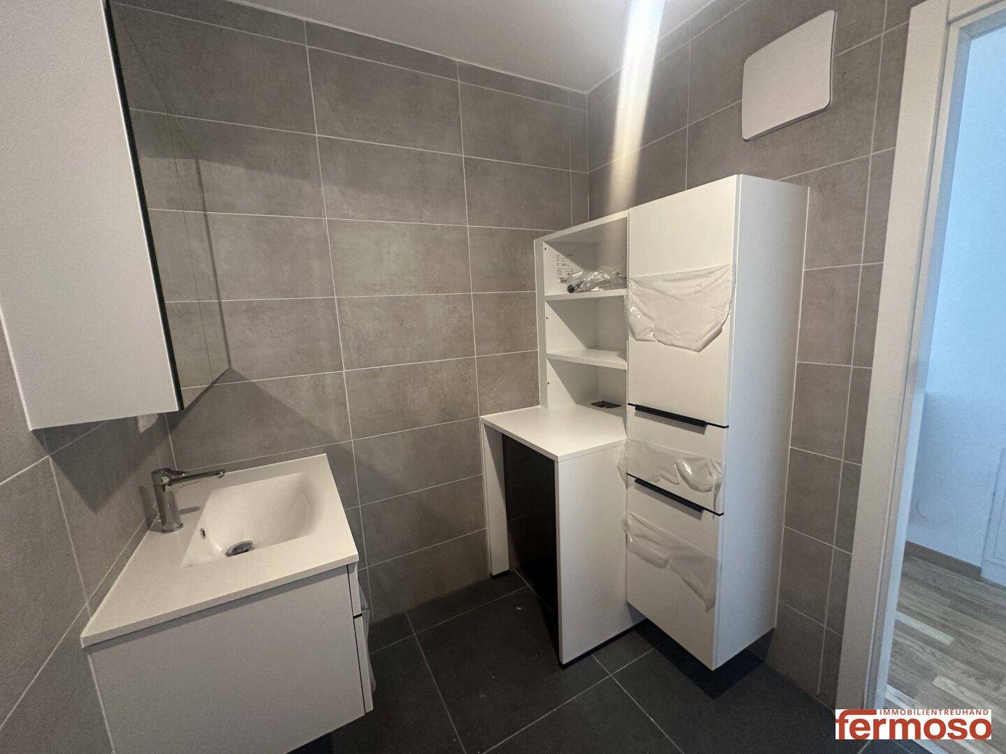 Badezimmer mit modernem Waschtisch und zusätzlichen weißen Aufbewahrungsschränken.