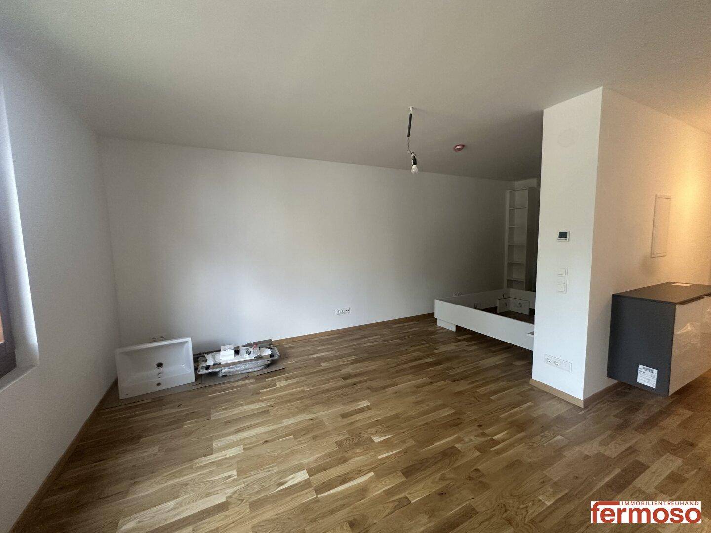 Geräumiger Wohnbereich mit hellem Holzparkettboden und viel Platz für Einrichtung.