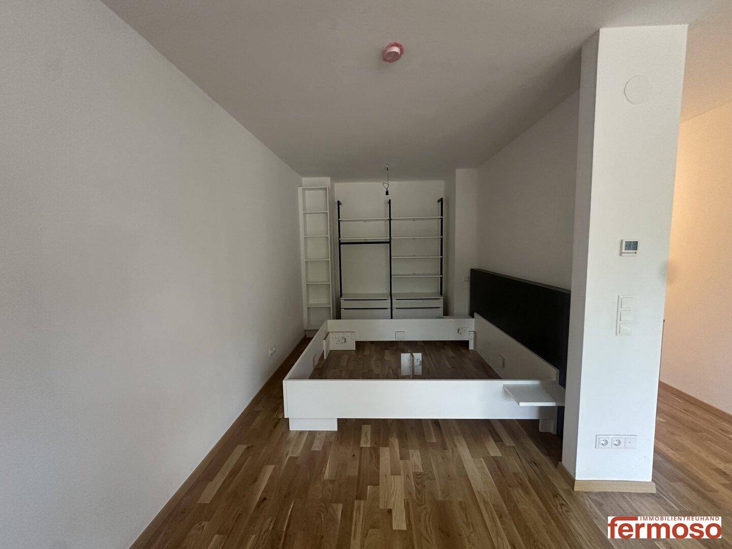 Schlafzimmerbereich mit Bettrahmen und integrierten Regalen, bereit zur Einrichtung.