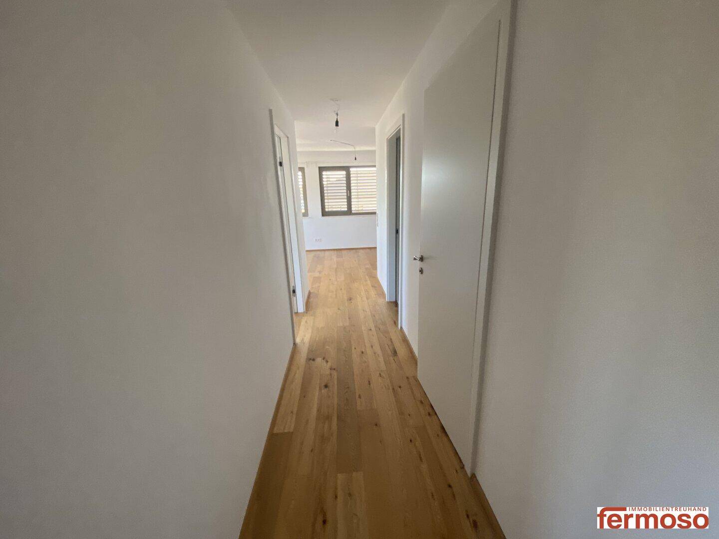 Langer Flur mit Holzboden, der verschiedene Räume der Wohnung verbindet.