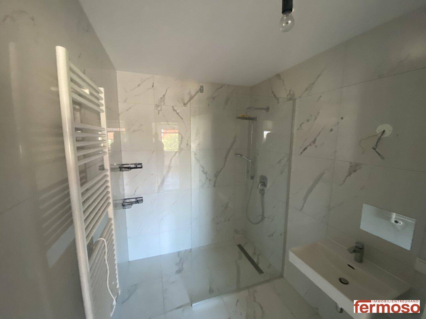 Modernes Badezimmer mit begehbarer Dusche, Handtuchheizkörper und Marmorfliesen.